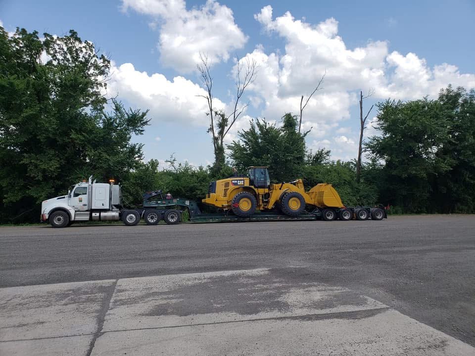 Kenworth tractor hauling a Cat 980 wheel loader on a multi-axle lowboy