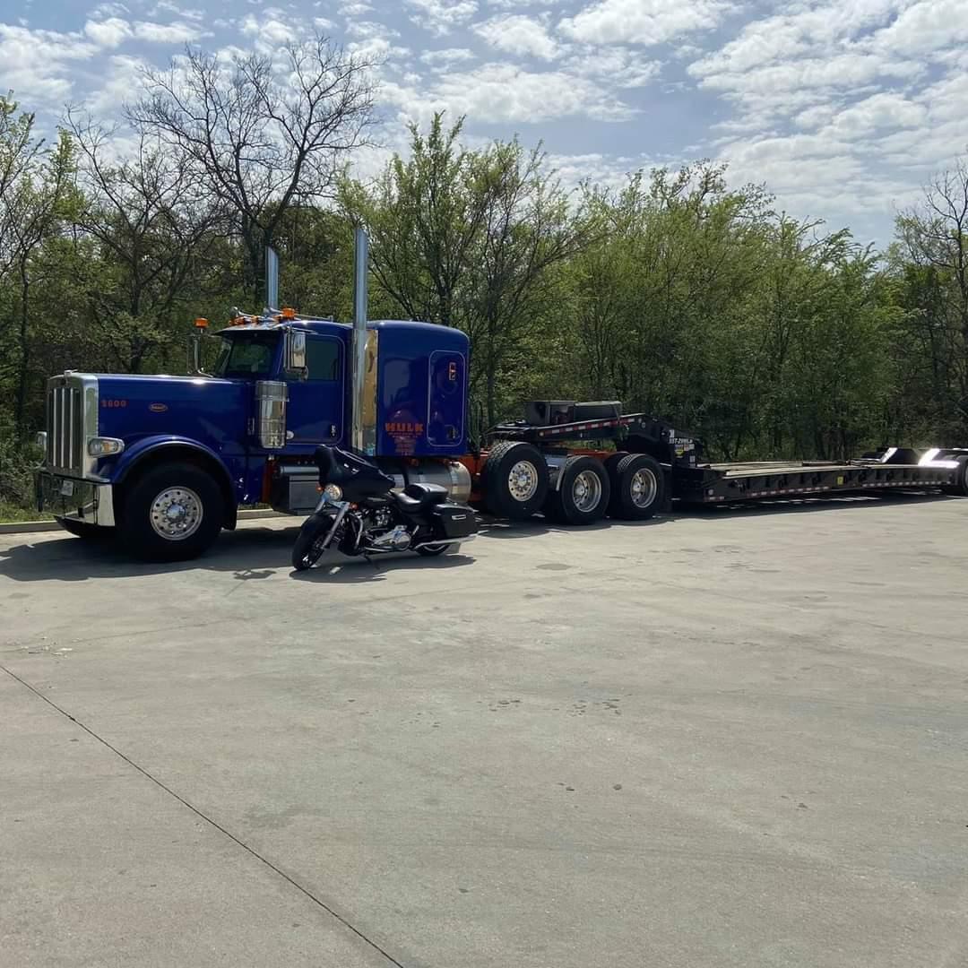 Blue Peterbilt tractor with a stretch lowboy trailer parked at the yard