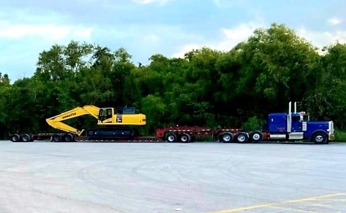 Blue Peterbilt lowboy hauling a yellow Komatsu excavator