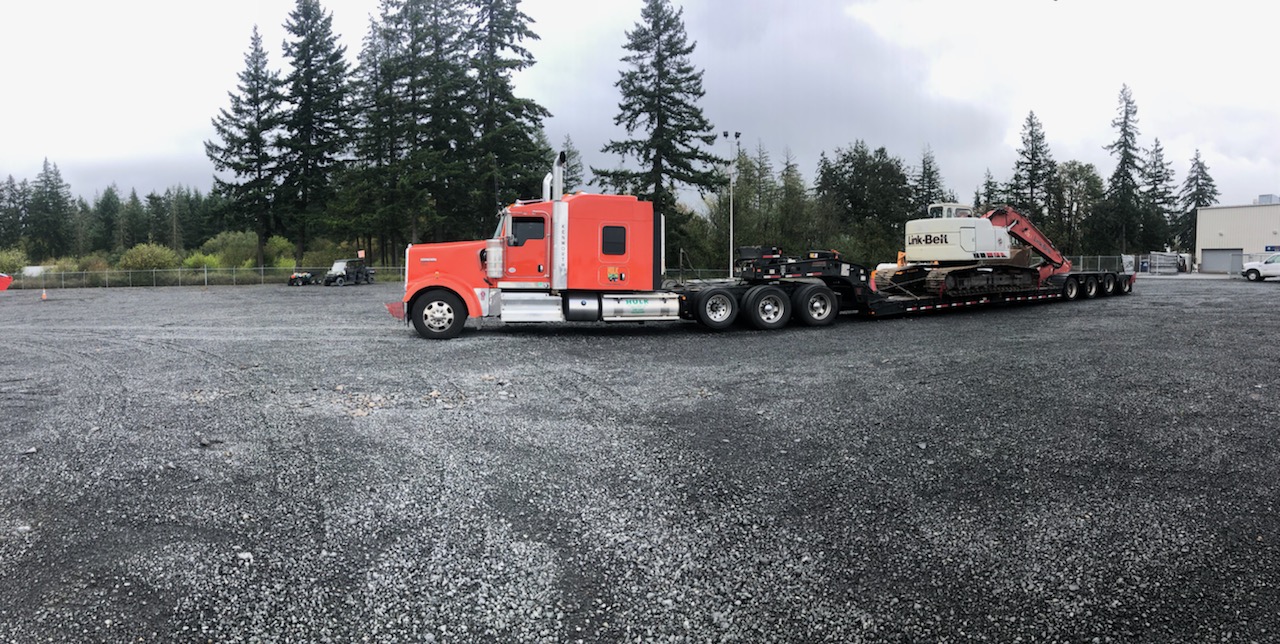 Orange Kenworth W900 with a Link-Belt excavator loaded on a lowboy trailer